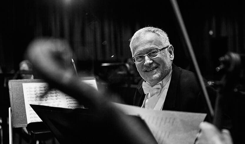 Zbigniew Dubik smiling over a music stand, in black and white.