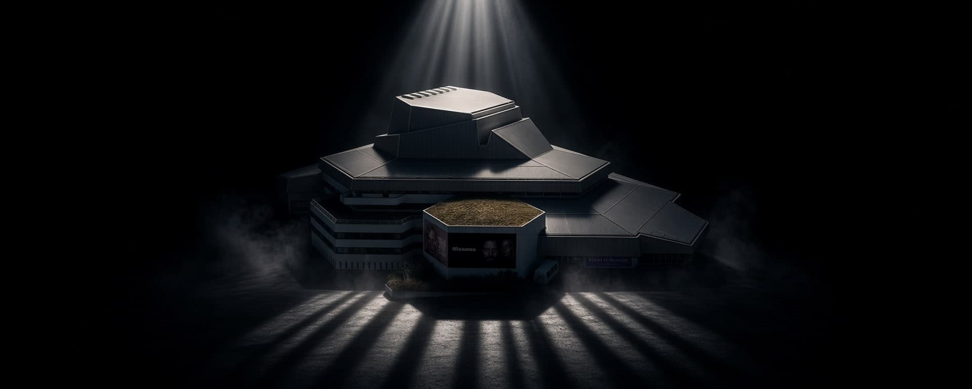Borgarleikhúsið under a single shaft of light against black. Grey roof planes step up in tiers and grass covers the roof above the entrance.