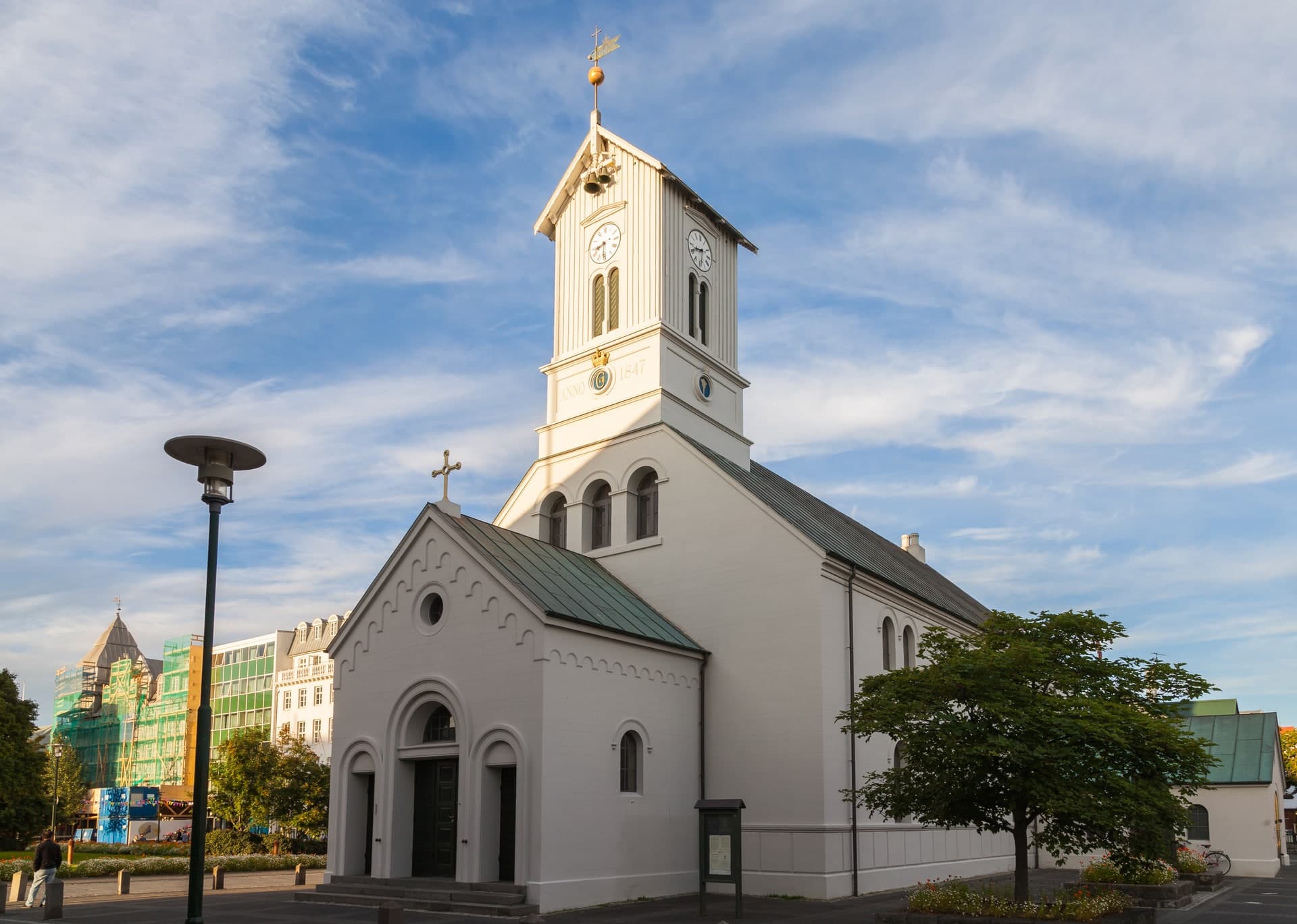 Dómkirkjan in Reykjavík in afternoon light, its pale front with an arch over the door and the clock tower rising from the roof.