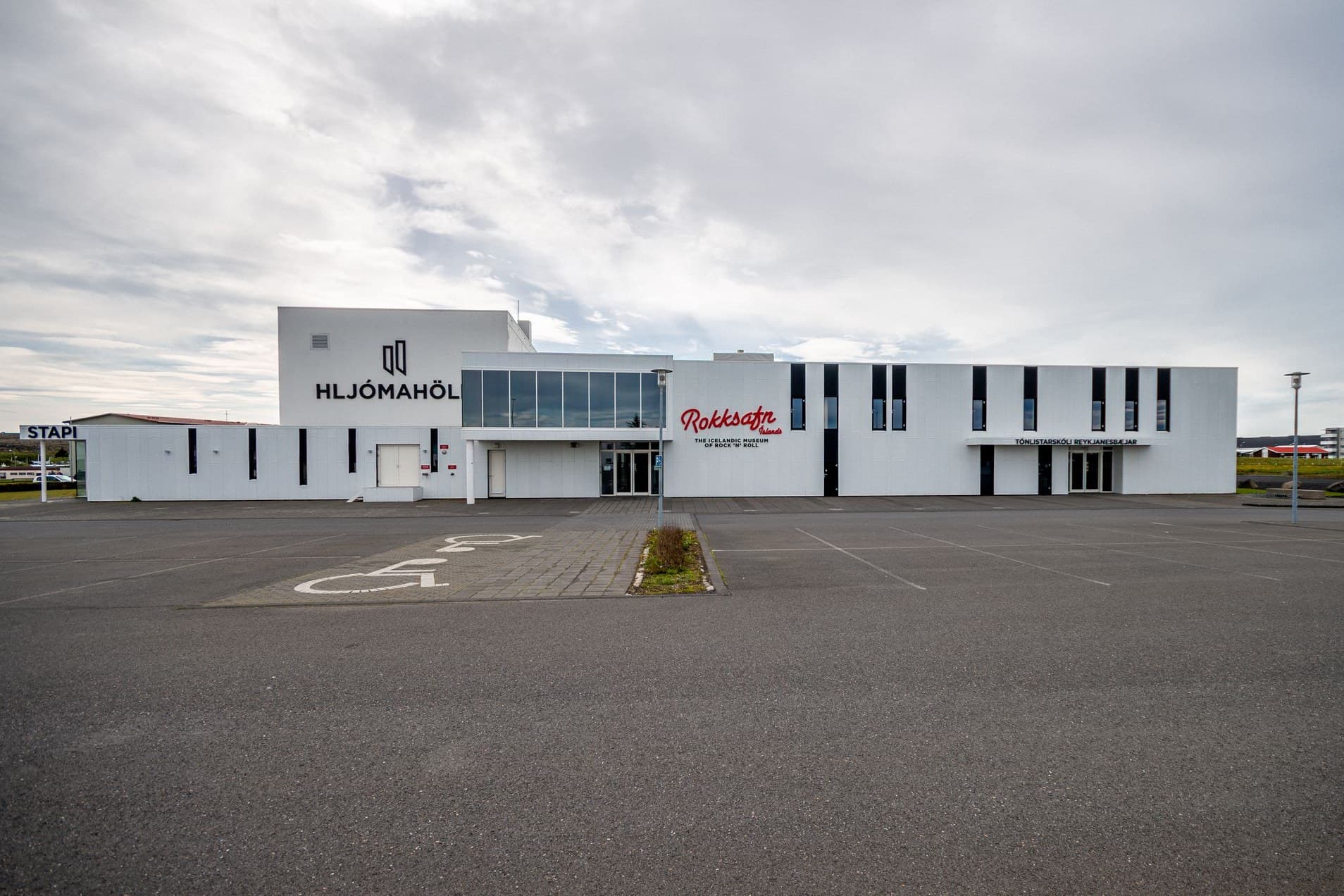 Hljómahöll frá bílastæðinu, hvít bygging með nafni hússins og merki Rokksafnsins á framhliðinni.