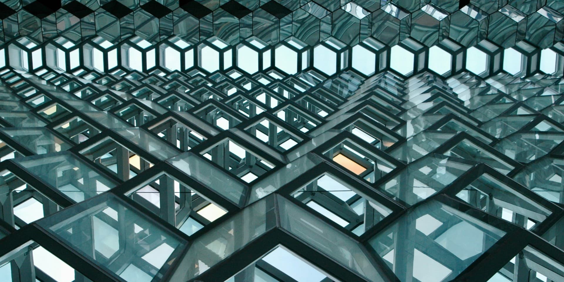 Geometric glass facade of Harpa Concert Hall in Reykjavík, looking up through hexagonal panels