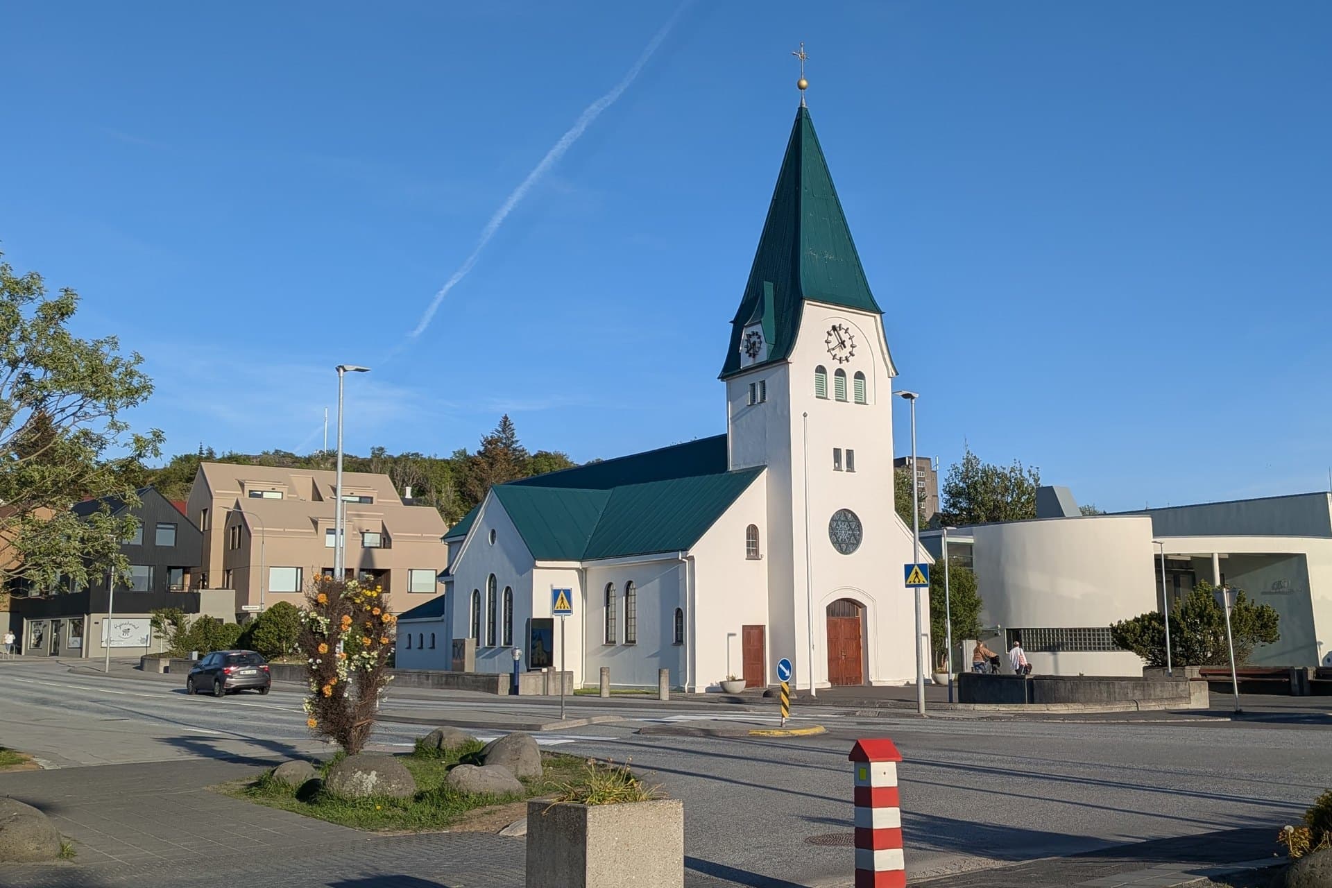 Hafnarfjarðarkirkja on Strandgata, a white church with a tall clock tower and a steep pointed roof, and the Strandberg parish hall to the right.